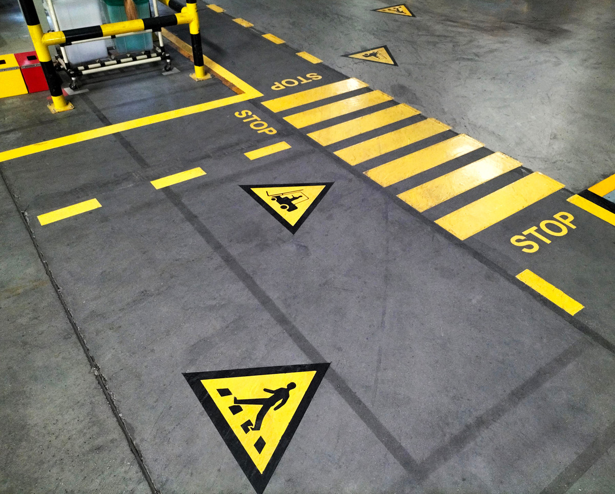 Yellow safety line marking painted on a warehouse floor.