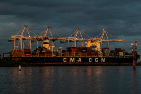 View of a ship docked at a wharf with dark clouds in the sky.